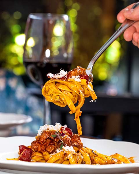 A pasta twirl hanging over a plate of food